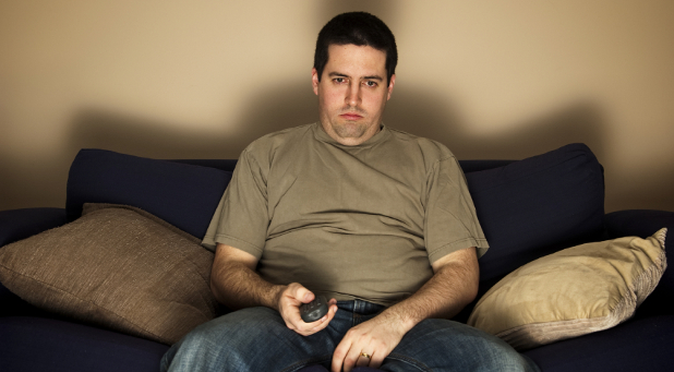Bored, overweight man sits on the sofa